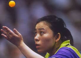 Tischtennisspielerin beim spannenden Aufschlag, Fokus auf orangefarbenem Ball, professionelle Intensität.