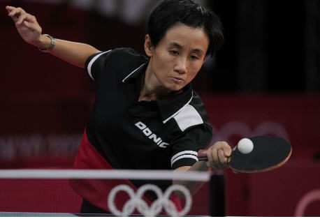 Olympische Tischtennis-Spielerin in Aktion, volle Konzentration und Präzision beim entscheidenden Vorhand-Schlag.