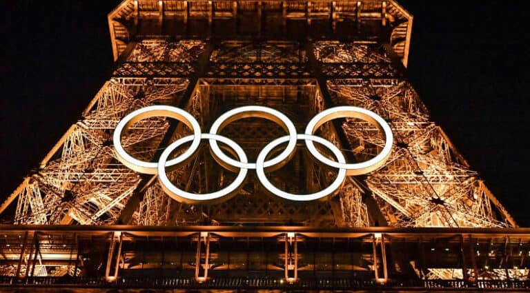 Nachts beleuchteter Eiffelturm mit olympischen Ringen, Symbol der bevorstehenden Olympischen Spiele in Paris.