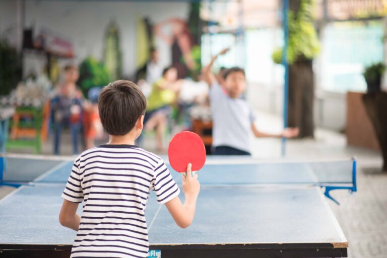 Kinder spielen Tischtennis im Freien mit Familie, genießen Sport und Gemeinschaft im Garten.