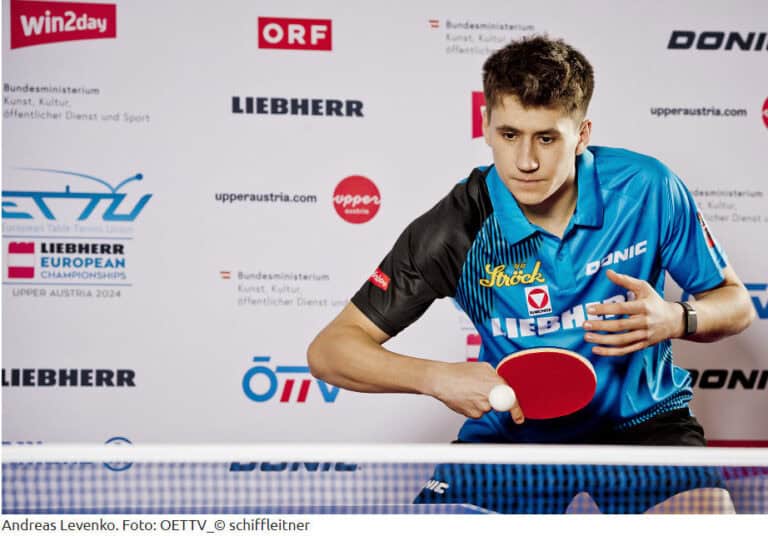 Junger Tischtennisspieler bei Europameisterschaft, konzentriert im Vorhandschlag, markanter Sponsorenhintergrund.