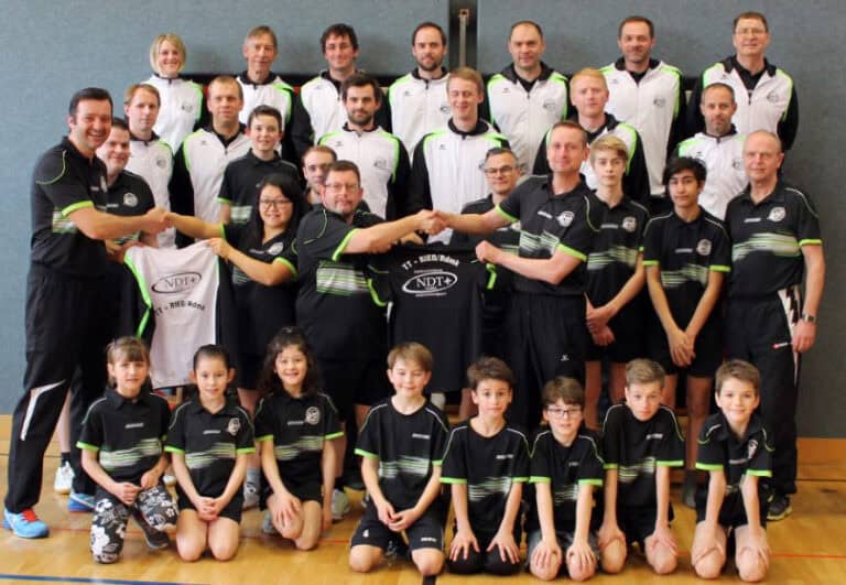Vereinsfoto von NDT+: Stolze Sportler in Gemeinschaftsbekleidung, symbolisiert Teamgeist und gemeinsame Errungenschaften.