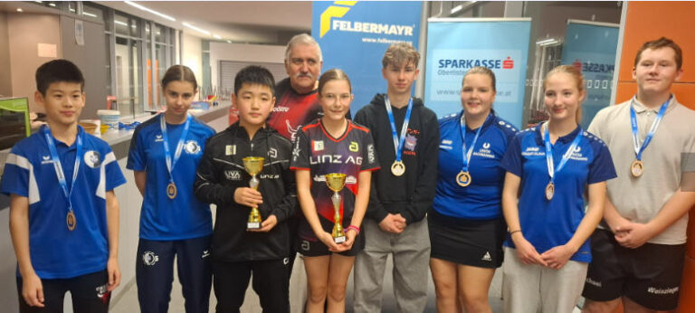 Junge Athleten feiern ihre Erfolge bei der Tischtennis-Meisterschaft mit Medaillen und Pokalen.